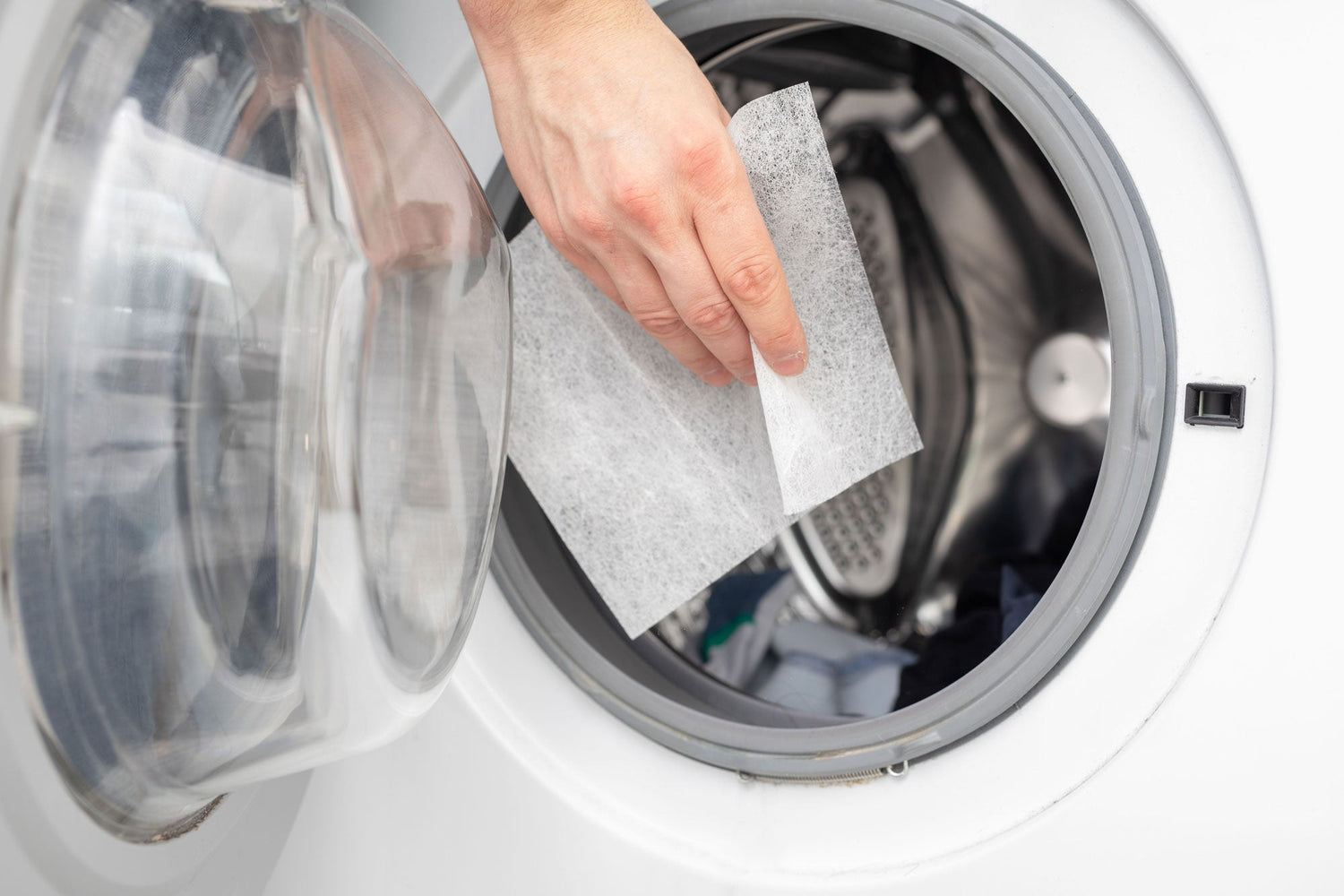 Hand dropping dryer sheet in the dryer